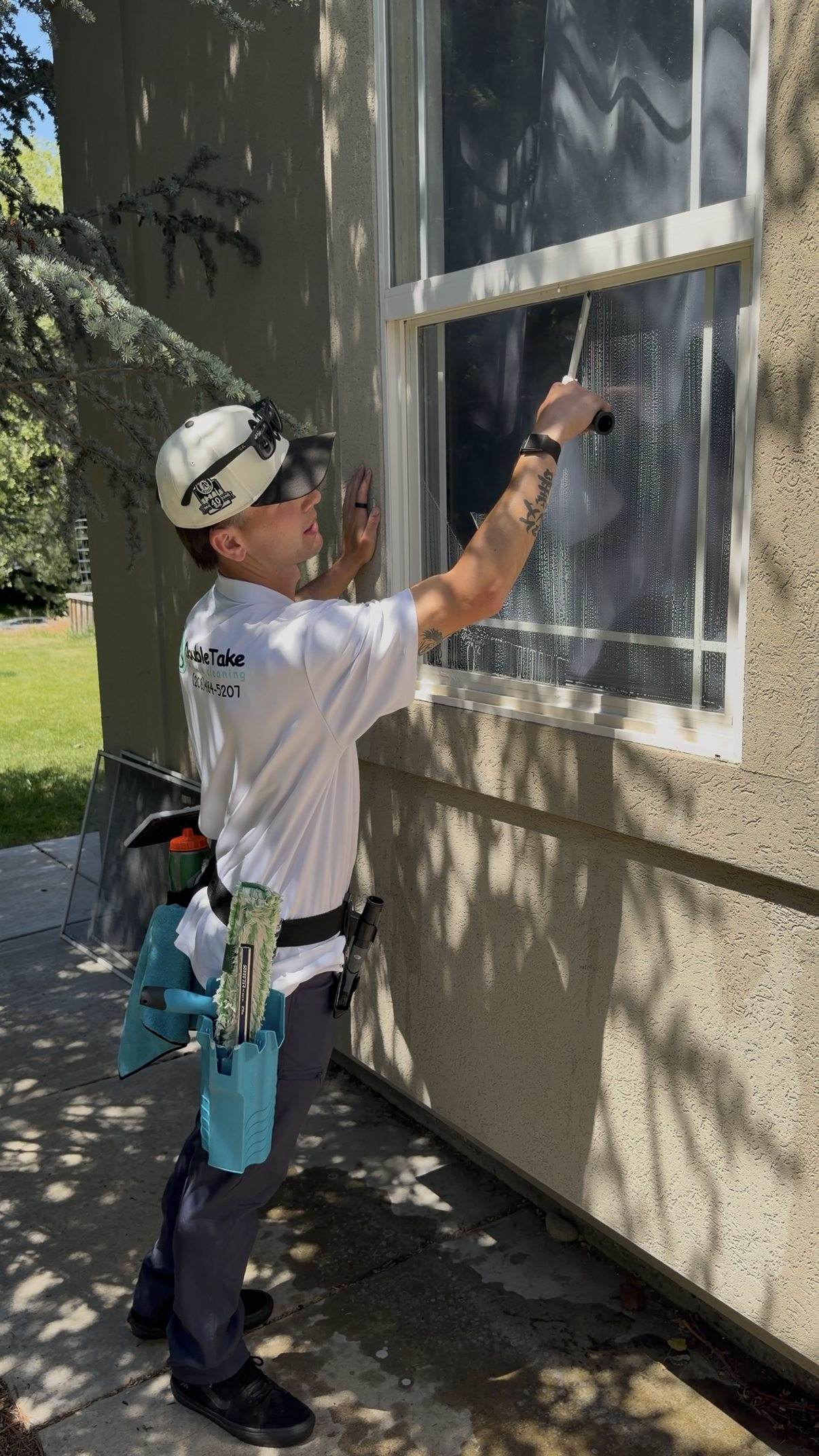 Double Take tech squeegeeing an exterior window on a stucco home.