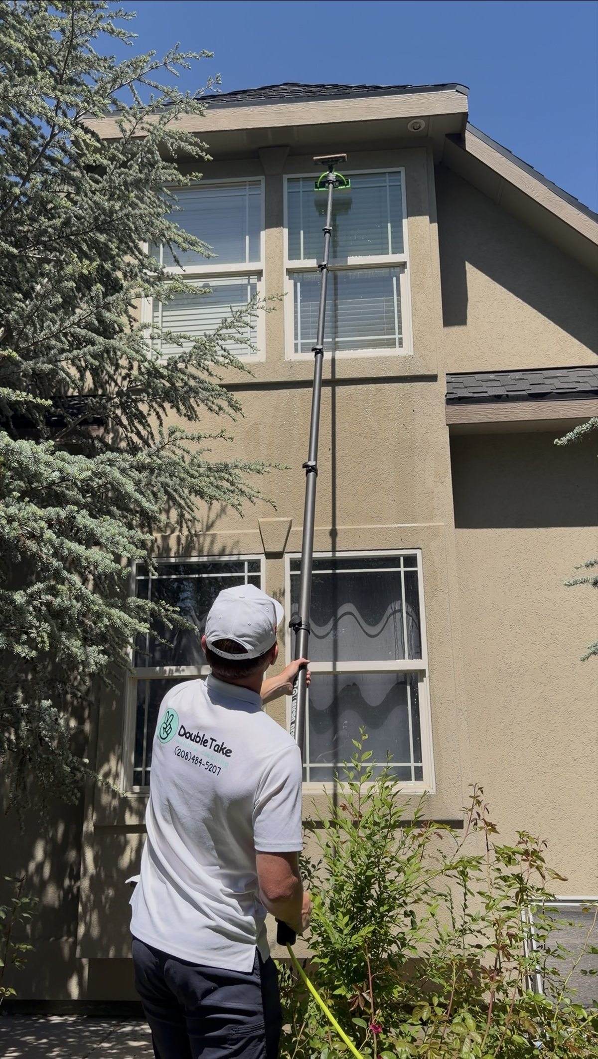Double Take tech scrubbing second-story windows with a water-fed pole.